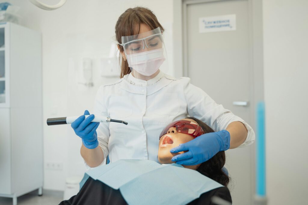 A female dentist using curing light on a patient in a modern dental clinic.