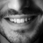 Black and white closeup of crop anonymous male with beard and mustache wearing casual t shirt